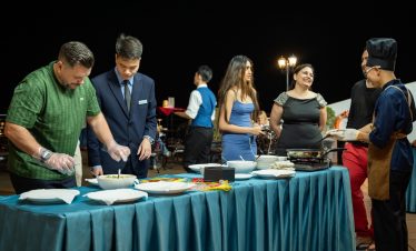 Guests enjoying a luxurious dinner on a cruise balcony in Lan Ha Bay at night.