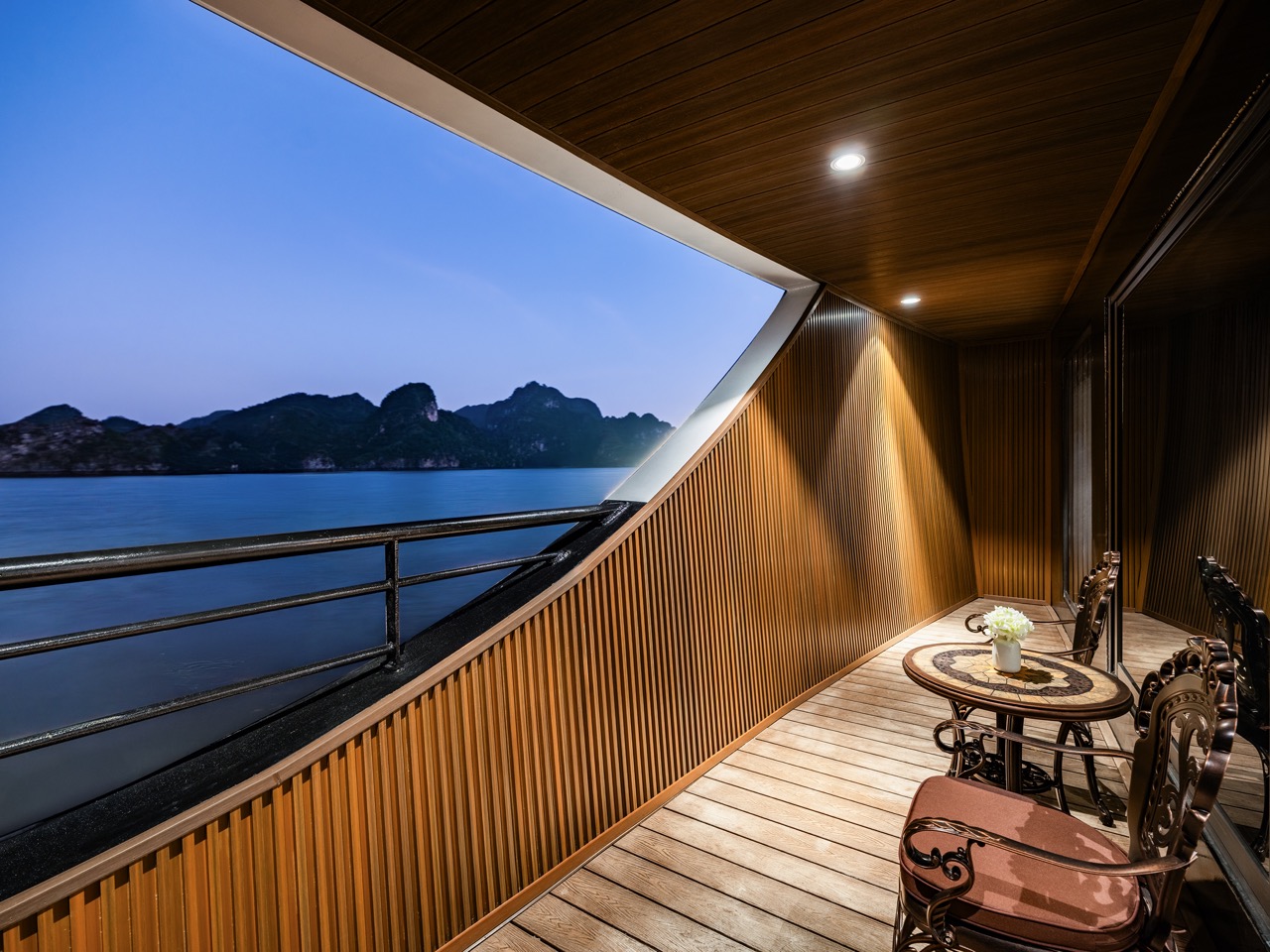 Stunning view from a cruise balcony in Halong Bay at dusk, showcasing tranquil waters and limestone.