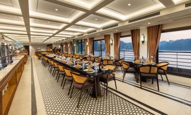 Elegant cruise dining room overlooking Halong Bay with panoramic windows and stylish decor.
