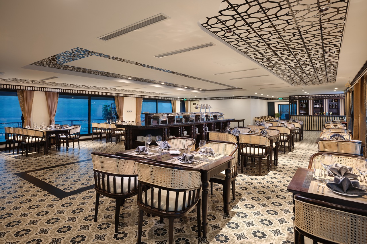 Luxurious cruise dining room with panoramic Lan Ha Bay views, elegant table settings, and modern dec.
