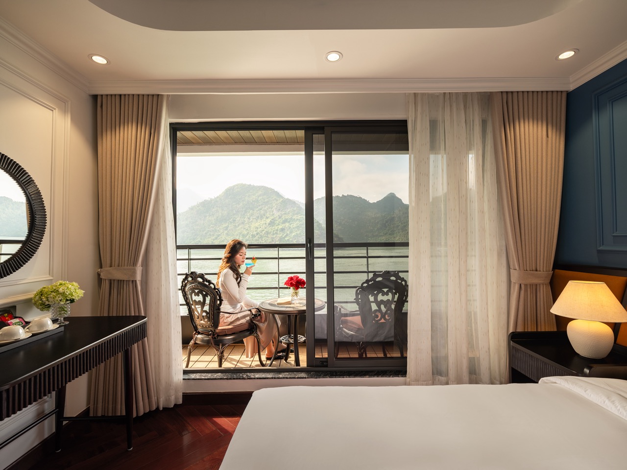 Relaxing woman enjoying Lan Ha Bay cruise balcony with stunning mountain views, luxury travel experi.