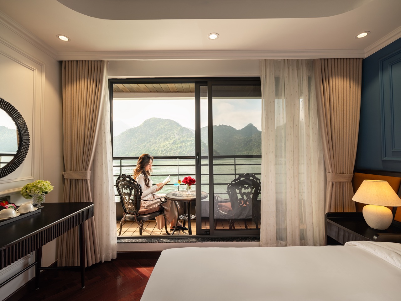 A woman enjoying a luxurious cruise balcony overlooking Lan Ha Bay's stunning limestone karsts, perf.