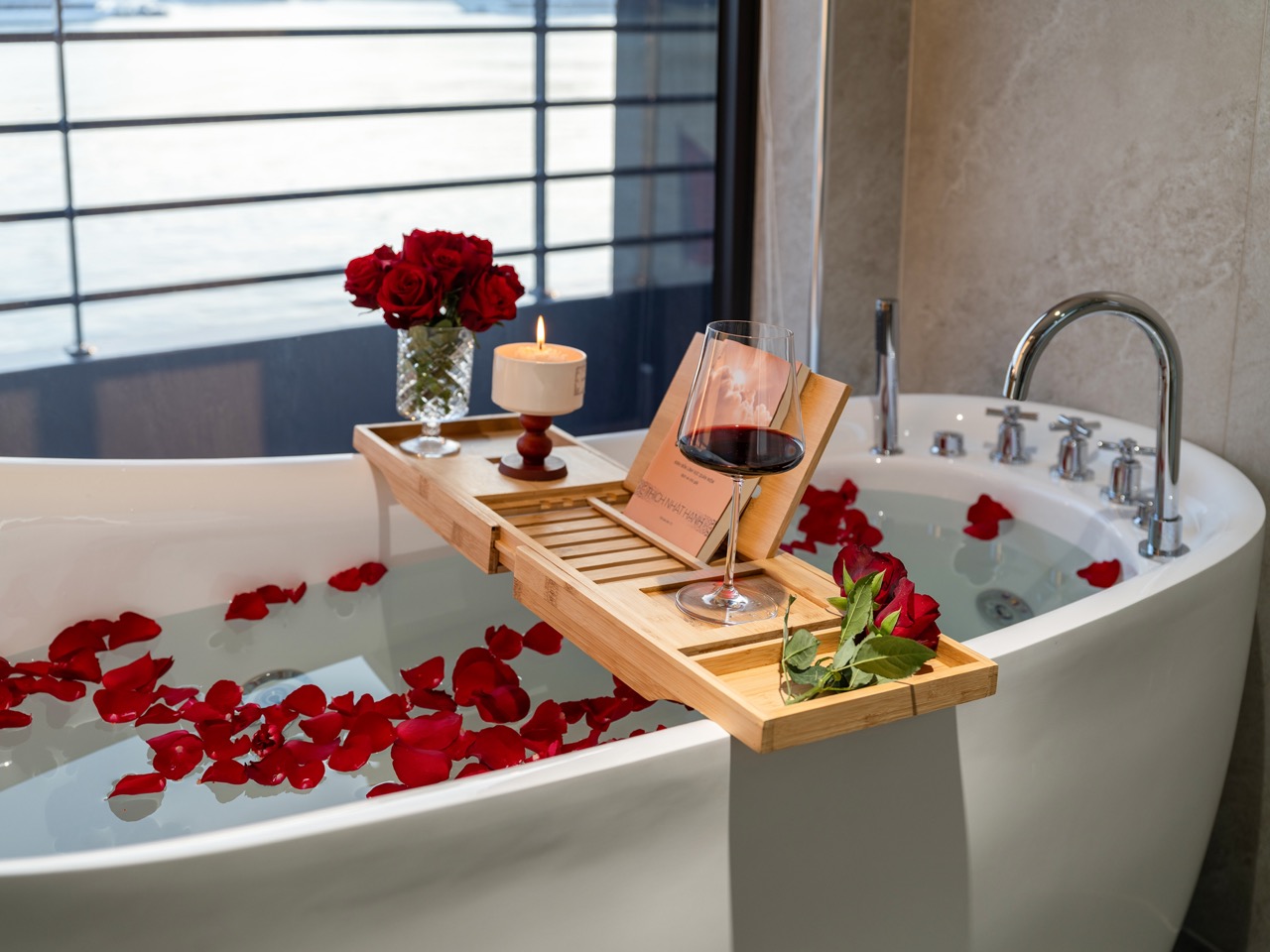 Scenic Halong Bay cruise balcony with rose petals, wine glass, and candle, offering a romantic and l.
