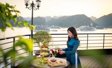 Scenic Lan Ha Bay cruise balcony with woman enjoying the sunset and panoramic views of limestone isl.