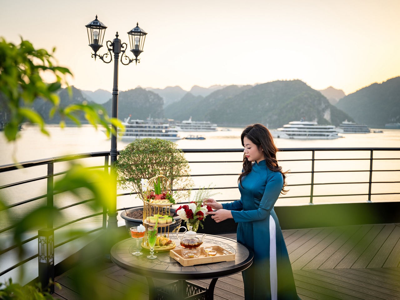 Scenic Lan Ha Bay cruise balcony with woman enjoying the sunset and panoramic views of limestone isl.