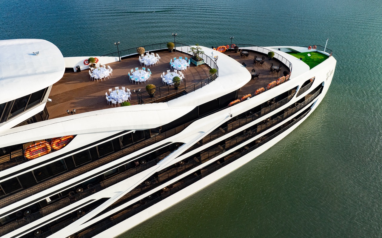 Stunning aerial view of a luxury cruise ship sailing in Lan Ha Bay, surrounded by emerald waters and.