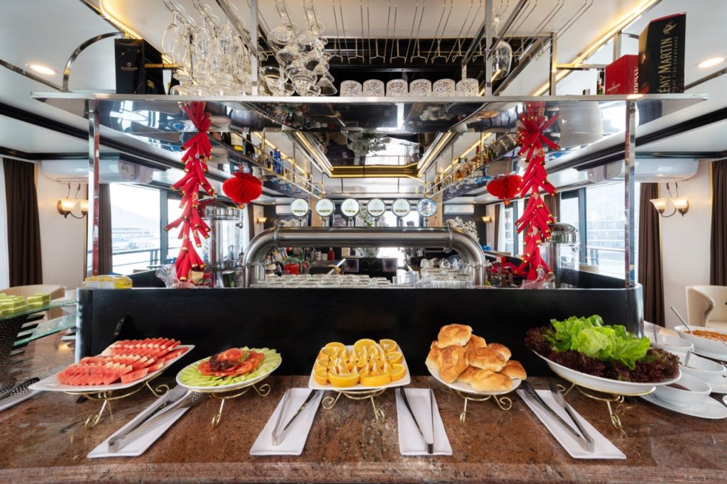 Luxury dining setup with fresh seafood and pastries on Lan Ha Bay cruise balcony, scenic bay view, e.