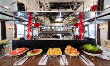 Luxury dining setup with fresh seafood and pastries on Lan Ha Bay cruise balcony, scenic bay view, e.