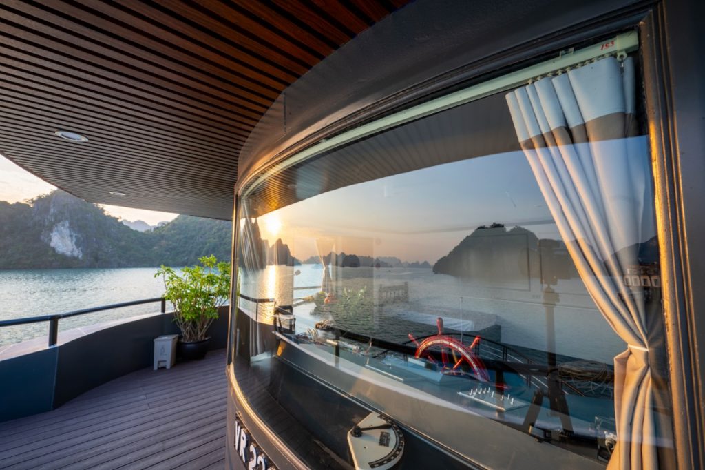Stunning Halong Bay scenery from cruise balcony with sunset reflection.