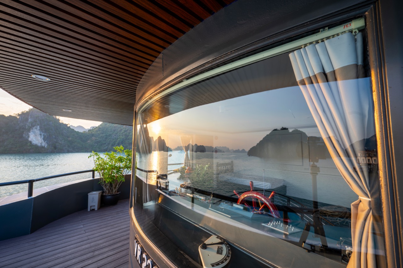 Stunning Halong Bay scenery from cruise balcony with sunset reflection.