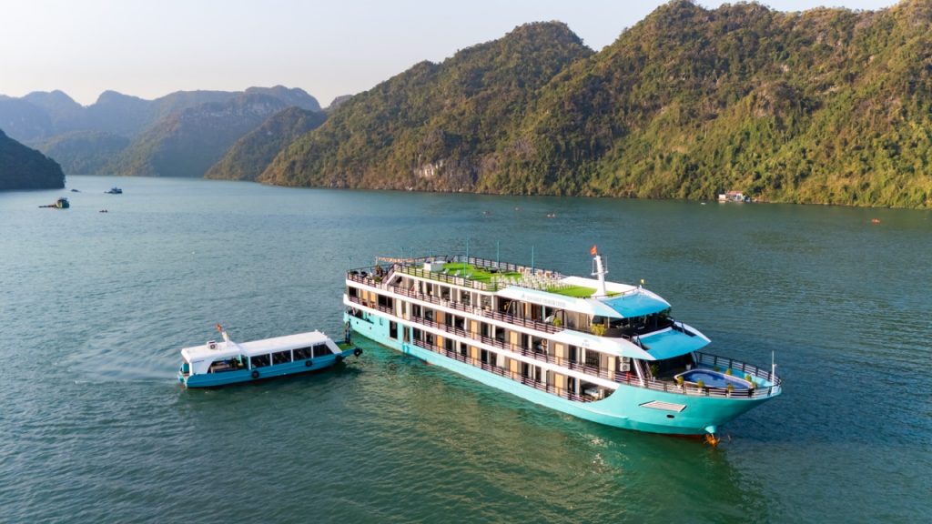 Luxurious cruise boat sailing on Lan Ha Bay with scenic limestone karsts and emerald waters.