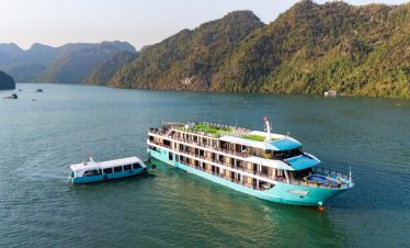 Luxurious cruise boat sailing on Lan Ha Bay with scenic limestone karsts and emerald waters.