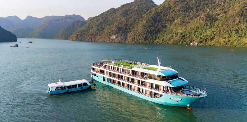 Luxurious cruise boat sailing on Lan Ha Bay with scenic limestone karsts and emerald waters.