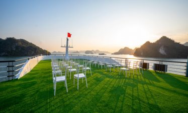 Sunset over Lan Ha Bay from cruise deck with chairs and scenic limestone islands, perfect for relaxi.
