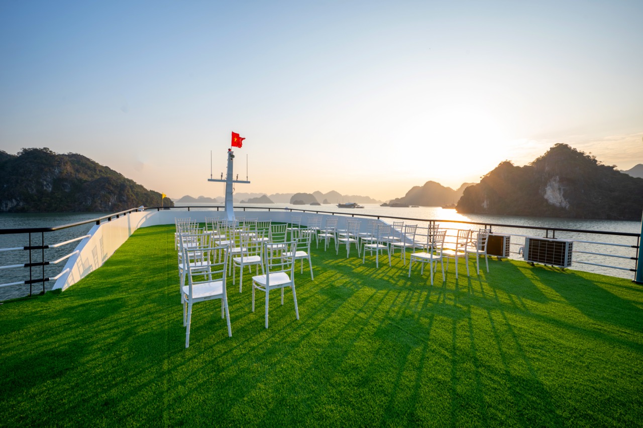 Sunset over Lan Ha Bay from cruise deck with chairs and scenic limestone islands, perfect for relaxi.