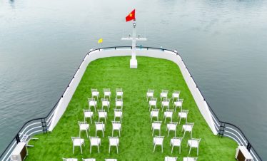 Beautiful Lan Ha Bay cruise deck with seating area and flag, perfect for relaxing and enjoying the v.
