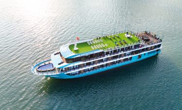 Aerial view of a luxury cruise in Lan Ha Bay with outdoor deck, sun loungers, and calm waters, perfe.