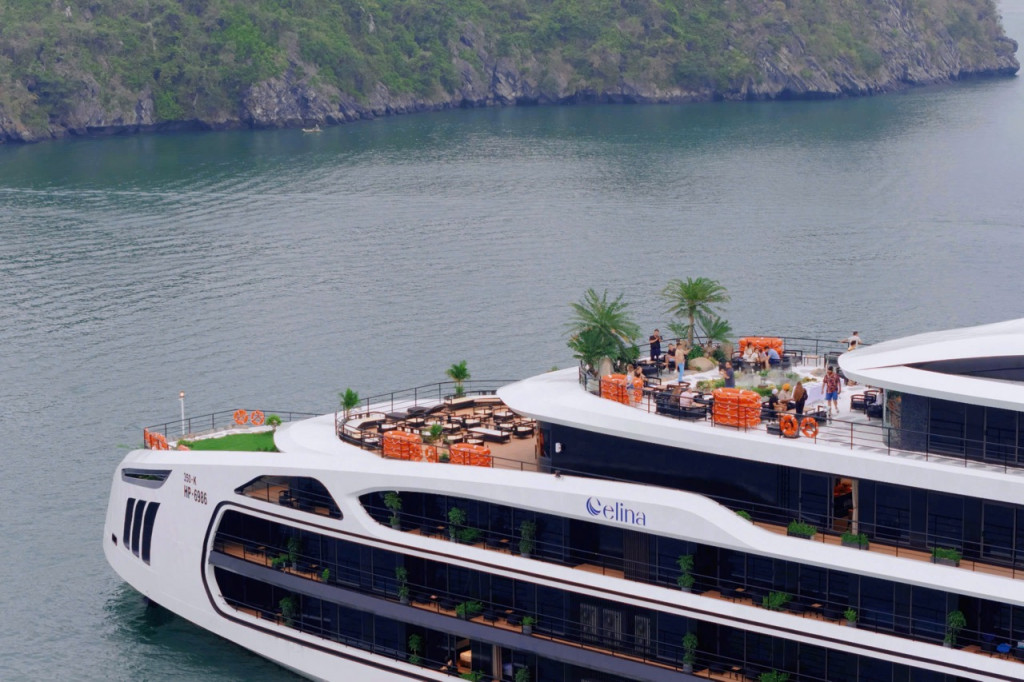 White multi-deck luxury cruise ship named Celina, with orange lifebuoys, palm trees, and guests on the top deck by the water.