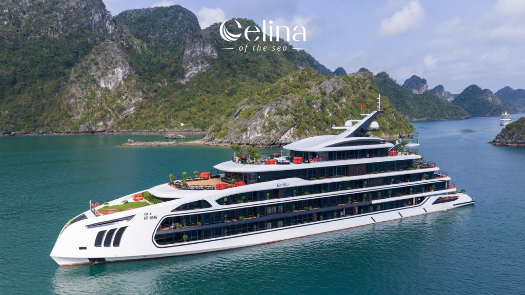 Luxurious white multi-deck yacht Celina of the Sea anchored in a turquoise bay with green limestone cliffs in the background.