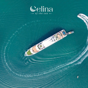 Aerial view of a white luxury yacht making a curved wake in clear turquoise water; Celina of the Sea logo at top.