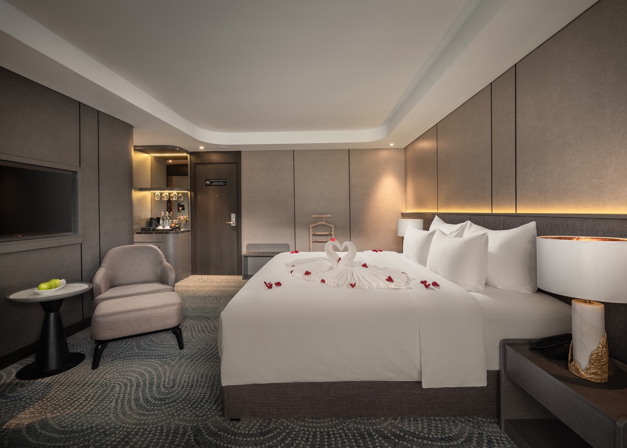 Hotel room with a king bed, swan towel sculpture and rose petals for a romantic setup, modern neutral decor.