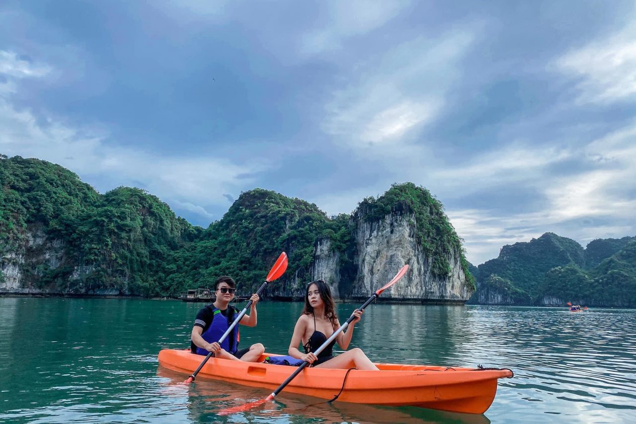 Kayakers exploring the stunning limestone karsts of Halong Bay on a peaceful day.